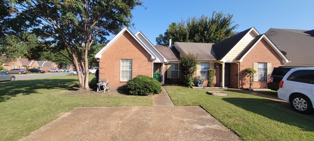a brick house with a driveway and trees